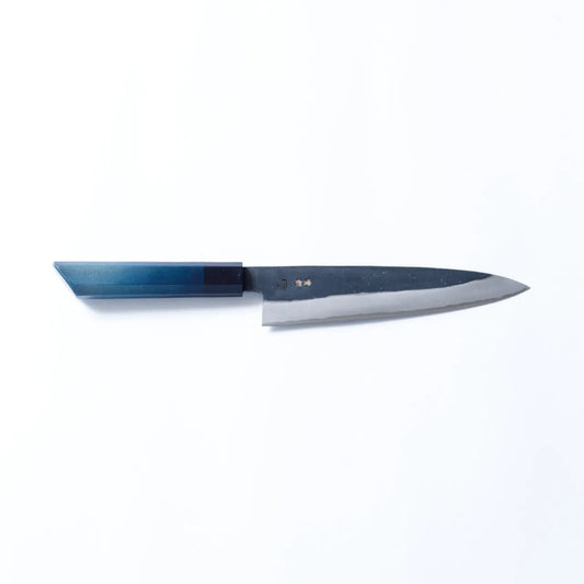 Cuchillo Gyuto artesanal de 210mm con hoja de acero al carbono forjado y mango teñido en añil, fabricado por maestros de Sakai y Tokushima.